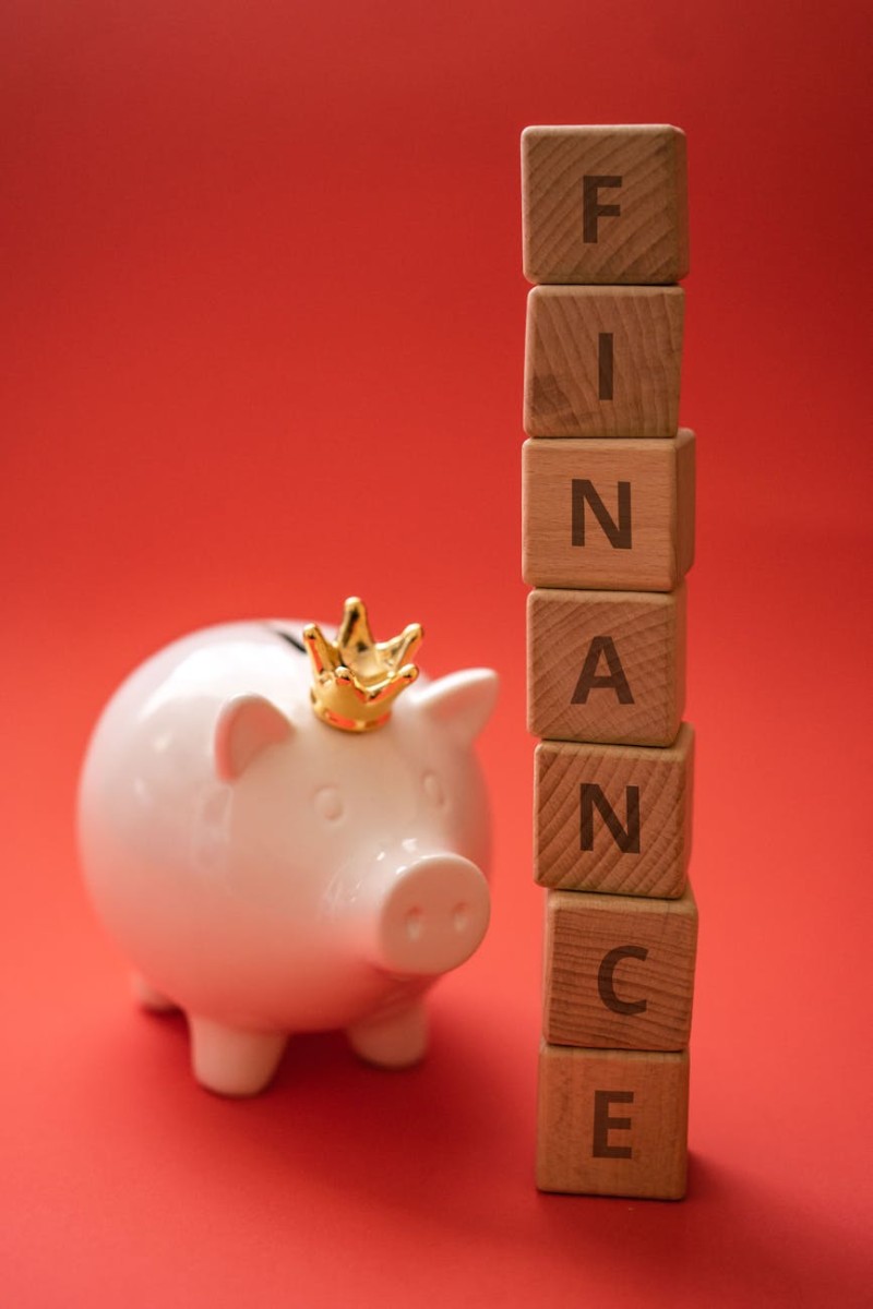 a pink piggy bank beside a stack of wooden scrabble blocks